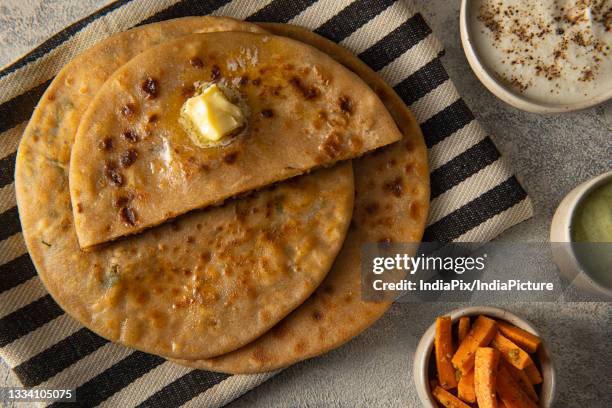 well cooked stuffed paranthas topped with butter served with appetizers - parantha stock pictures, royalty-free photos & images