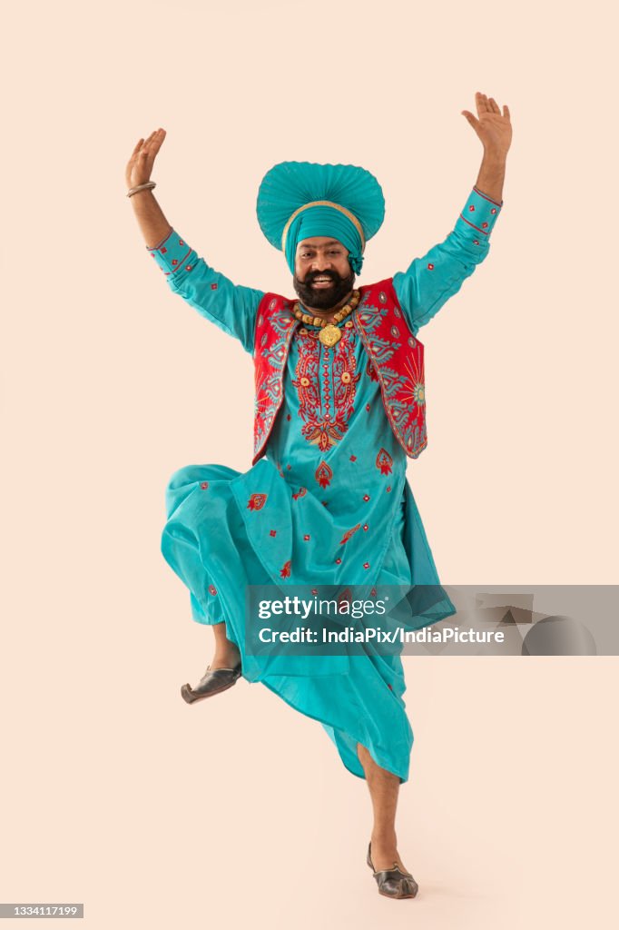A Bhangra dancer demonstrating a dance step with hands in the air.