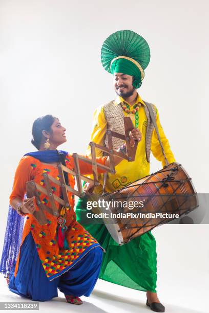 a bhangra and a giddha dancer performing with a dhol and saap. - punjab stock pictures, royalty-free photos & images