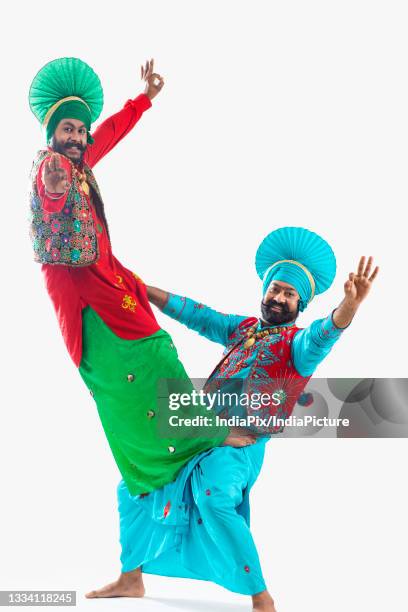 two bhangra dancers striking a classic step of their dance form. - folk music stock pictures, royalty-free photos & images