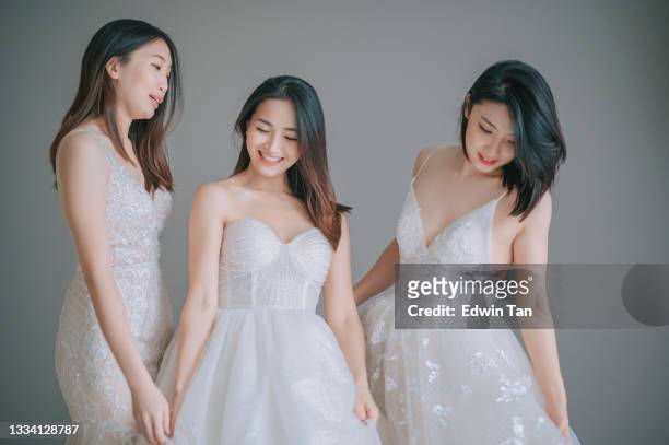 bride and bridesmaid in a row with gray wall getting ready smiling happily - chinese wedding dress stock pictures, royalty-free photos & images