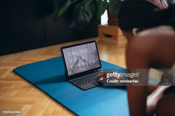 unrecognizable fitness woman watching training videos on tablet at home - home workout stockfoto's en -beelden