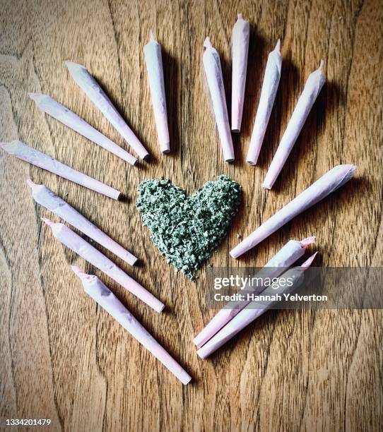 heart shaped pile of green dried herb with pink joints - cannabis droge stockfoto's en -beelden