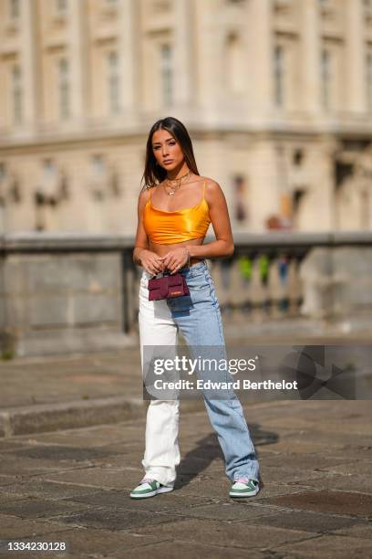 Isabeau Delatour @isabeau.delatour wears large gold chain pendants necklaces, a yellow V-neck cropped tank-top, gold large chain bracelets, a silver...