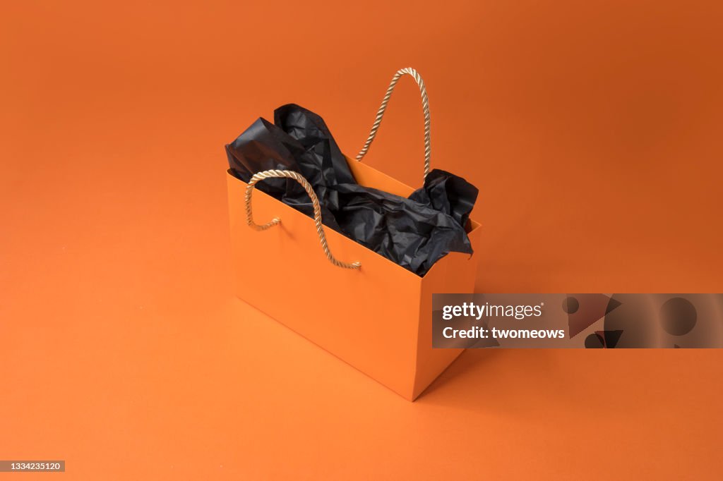 One orange colour shopping bag on orange background.