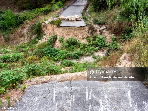 road cut in a ravine that crosses a river destroyed by a flood. - lerskred bildbanksfoton och bilder