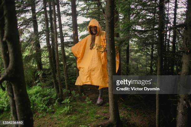 happy woman in the orange raincoat in the forest - female rain coat stock pictures, royalty-free photos & images