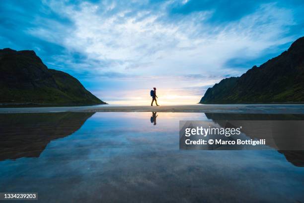 person walking on the baech at sunset, senja, norway - symmetry stock pictures, royalty-free photos & images