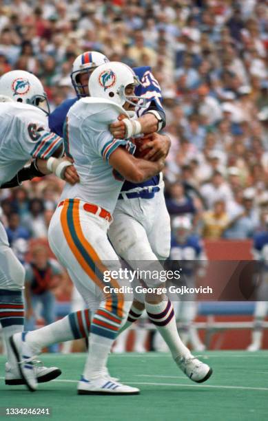 Running back Larry Csonka of the Miami Dolphins runs with the football as linebacker Jim Haslett of the Buffalo Bills attempts to tackle him during a...