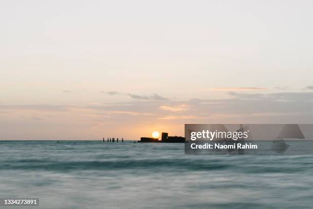 sun setting over shipwreck in half moon bay, melbourne - 下沉的 個照片及圖片檔