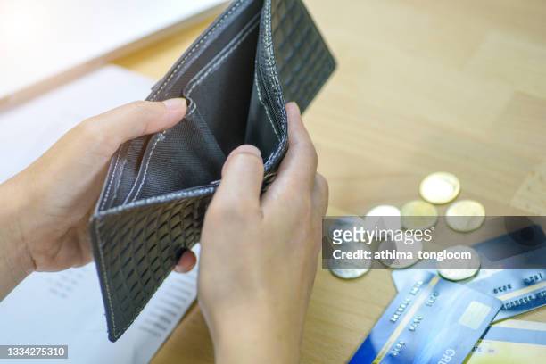man holding an empty wallet and few coins. - empty wallet stock pictures, royalty-free photos & images