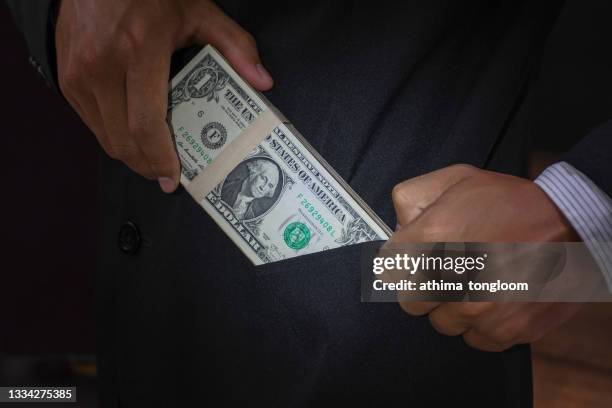 man putting bribe money into his pocket. - corrupt politician stock pictures, royalty-free photos & images