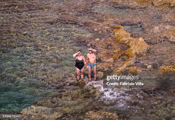 Couple holds hands while swimming in the sea on Ferragosto day on August 15, 2021 in Siracusa, Italy. Earlier this week, Sicily saw temperatures...