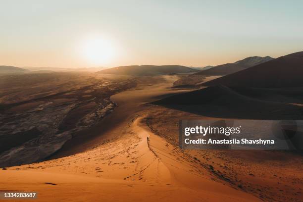 ナミブ砂漠の砂丘で風光明媚な夕日を楽しむ男の旅行者 - desert ストックフォトと画像