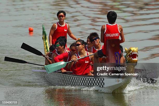 The Singapore Women's 12 crew cross the finish line during traditional boat racing on day nine of the 2011 Southeast Asian Games at Danau Cipule on...