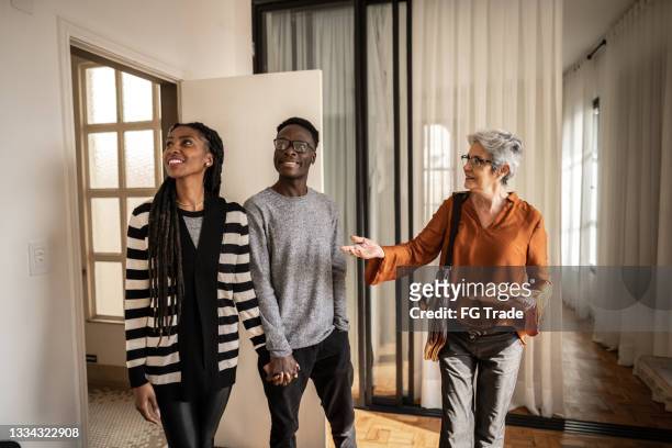 real estate agent showing apartment to young couple - visitor stock pictures, royalty-free photos & images