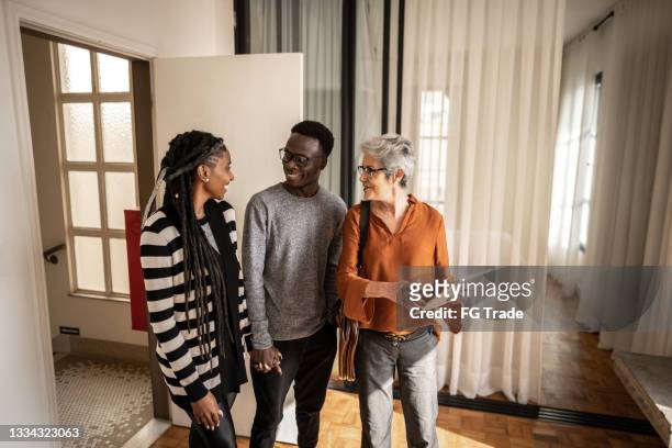 real estate agent showing apartment to young couple - bezoek stockfoto's en -beelden