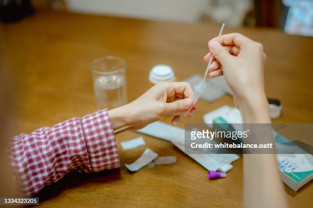 young woman drops swab in a protective plastic tube. - covid 19 test stock pictures, royalty-free photos & images