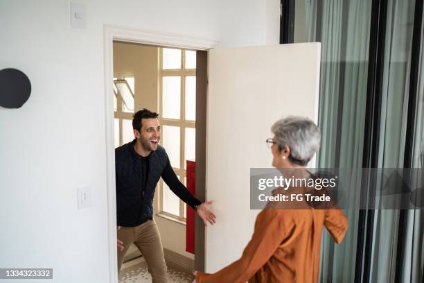 senior woman greeting son at home - surprise guest stock pictures, royalty-free photos & images