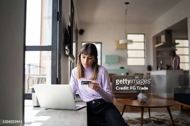young woman doing online shopping using credit card at home - online shopping stock pictures, royalty-free photos & images