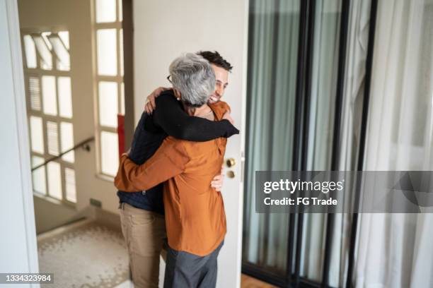 senior woman greeting son at home - open roads world premiere of mothers day arrivals stockfoto's en -beelden