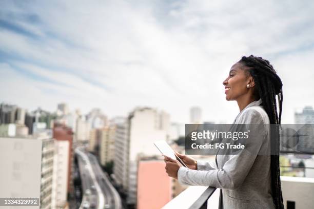 junge geschäftsfrau, die auf einem dach über digitales tablet nachdenkt und es benutzt - são paulo city stock-fotos und bilder