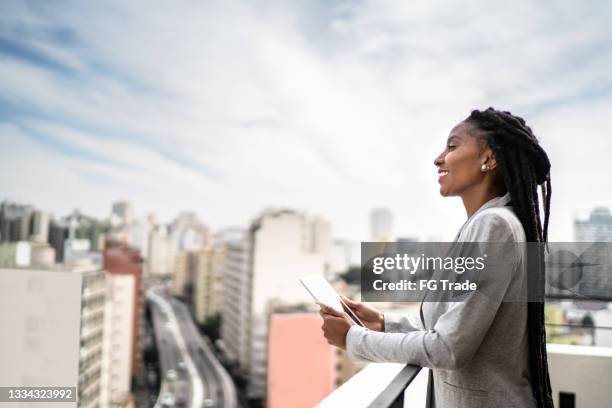 young businesswoman contemplating and using digital tablet in a rooftop - vision and mission stockfoto's en -beelden