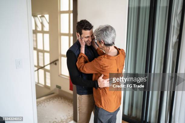 senior woman greeting son at home - open roads world premiere of mothers day arrivals stockfoto's en -beelden