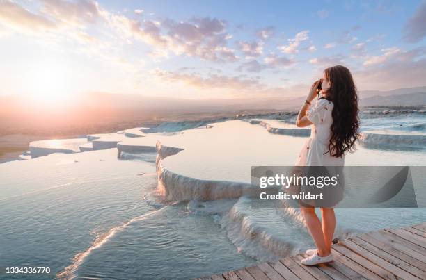 beautiful traveller photographer girl is taking photos at travertine pools during sunset in pamukkale - pamukkale stockfoto's en -beelden