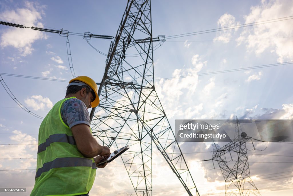 Engineers in front of power plant using digital tablet