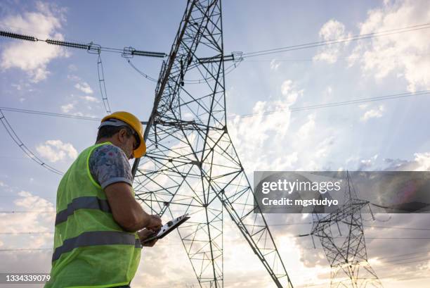 engineers in front of power plant using digital tablet - rede elétrica imagens e fotografias de stock
