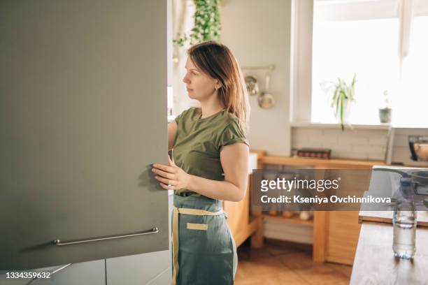 young woman in front of the fridge - keep photos et images de collection