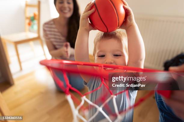 süßer kleiner junge, der spaß beim basketballspielen mit den eltern zu hause hat - cute basketball players stock-fotos und bilder
