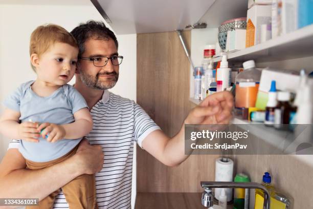 papai e seu filho bebê tomando remédios fora do armário de remédios - armário de banheiro - fotografias e filmes do acervo