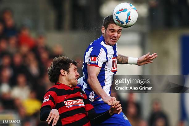 Pierre-Michel Lasogga of Berlin outjumps Julian Schuster of Freiburg during the Bundesliga match between SC Freiburg and Hertha BSC Berlin at...