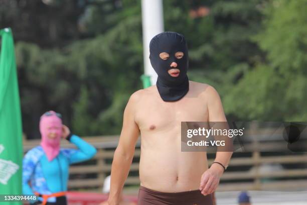 Citizen wearing facekini prepares to cool off in the sea on August 14, 2021 in Qingdao, Shandong Province of China.
