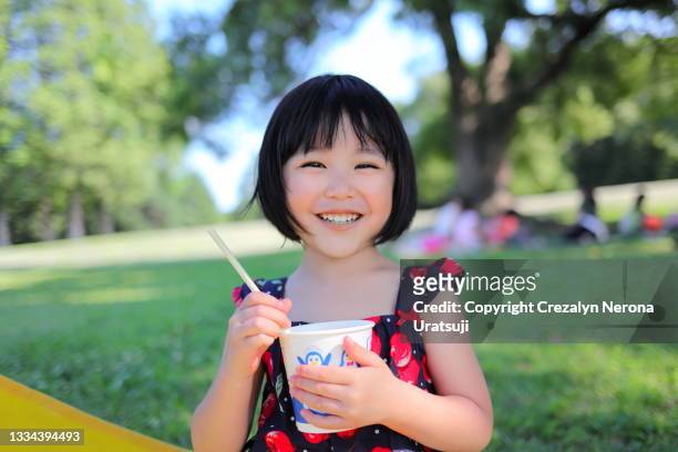 little child satisfied with melon flavor shave ice smiling and looking at camera in summer - japanese girl fotografías e imágenes de stock