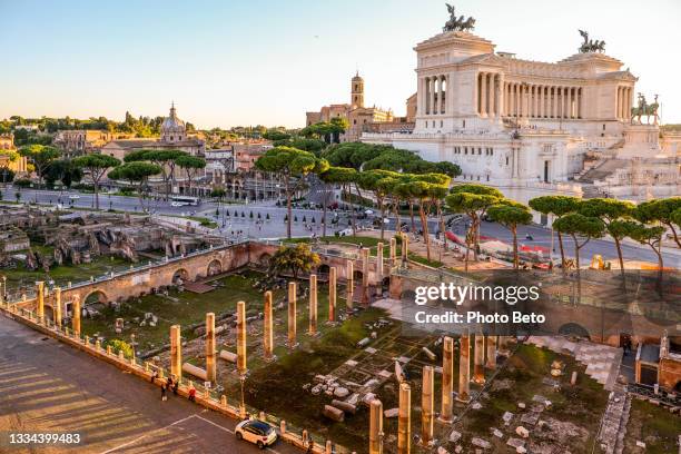 la luce calda del tramonto illumina il foro di traiano a roma con l'altare della patria sullo sfondo - altare della patria foto e immagini stock