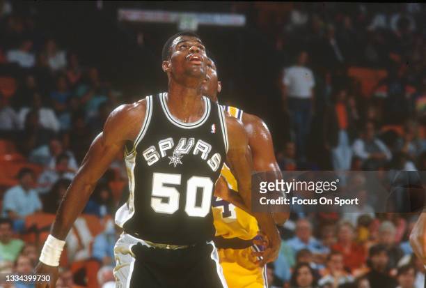 David Robinson of the San Antonio Spurs battles for position with Sam Perkins of the Los Angeles Lakers during an NBA basketball game circa 1990 at...