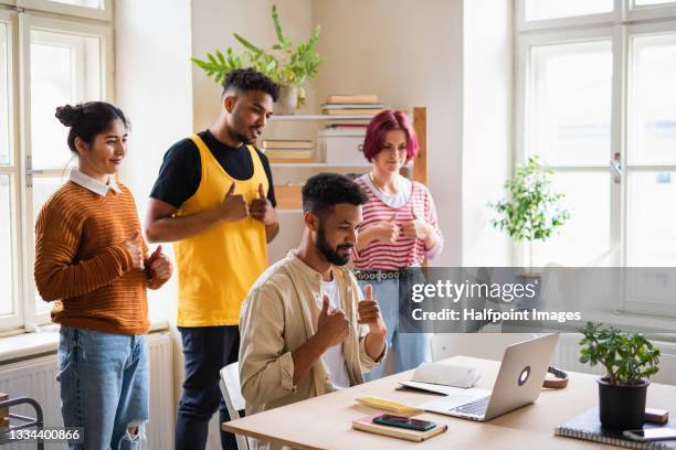 group of young people with laptop using sign language indoors in office, start up concept. - group of people using sign language stock pictures, royalty-free photos & images