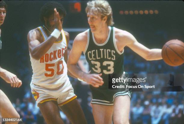 Larry Bird of the Boston Celtics dribbles the ball while being defended by Robert Reid of the Houston Rockets during an NBA basketball game circa...