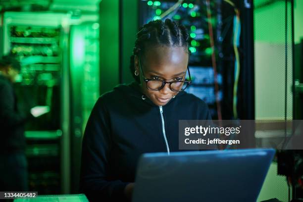 scatto di una giovane programmatrice di computer femminile che usa un laptop mentre si trova in una stanza buia del server - person on computer in dark room foto e immagini stock