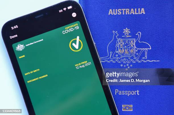 This image has been digitally manipulated.) A mobile phone with an Australian Covid-19 certificate on it next to an Australian passport on August 15,...