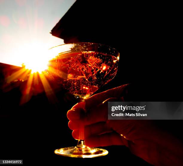 woman hand holding a glass with rose champagne in a sunny summer day with sunbeam - valais canton stock pictures, royalty-free photos & images