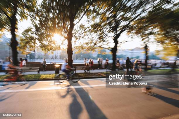 defocused autumn cityscape background, unknown people relaxing in the public park - backgrounds people stock-fotos und bilder