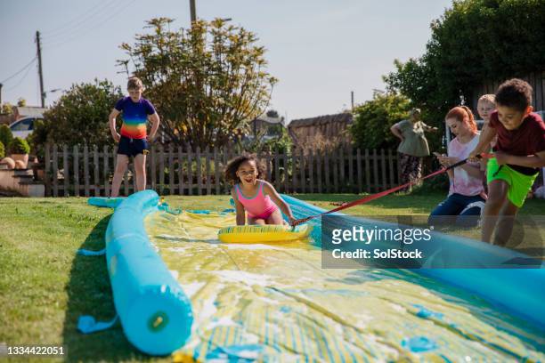having the best day with a slip n slide - backyard water slide stock pictures, royalty-free photos & images