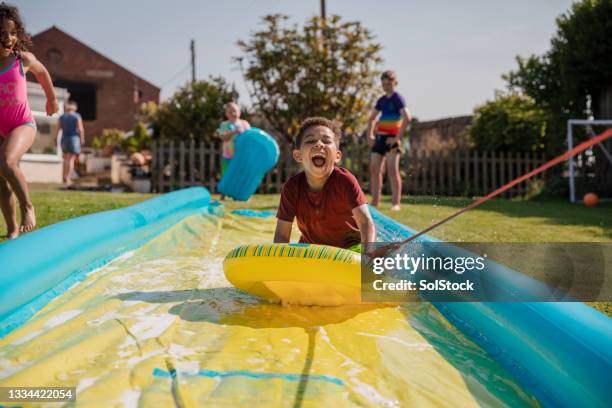 playing on the slip n slide - water slide stockfoto's en -beelden