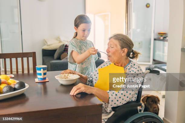 young girl feeds grandmother at home - woman home with sick children imagens e fotografias de stock