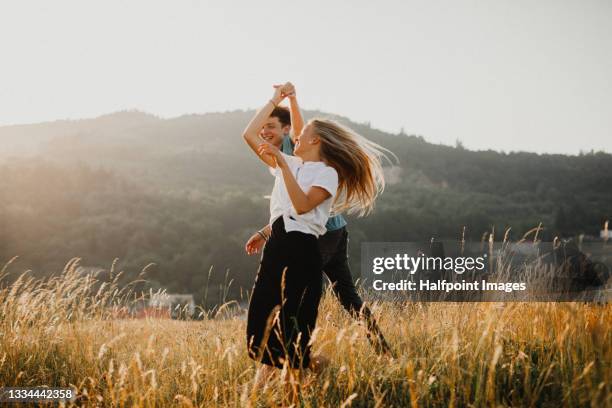 portrait of young couple on a walk outdoors in nature, dancing. - young couple enjoying a walk through grassland stock pictures, royalty-free photos & images