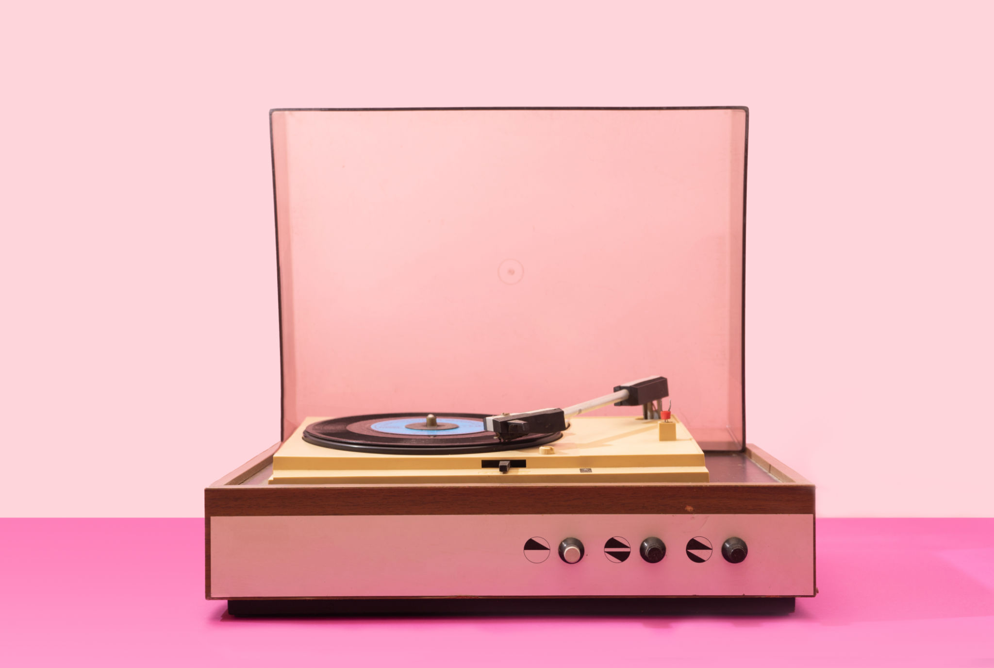 Gramophone record player from sixties. Turntable for single vinyl with pink bottom with light pink background. Gramophone record player from sixties. Turntable for single vinyl with pink bottom with light pink background.